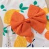 Orange bow on lemon-patterned fabric.